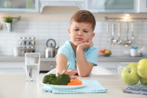 Adorable,little,boy,refusing,to,eat,vegetables,at,table,in